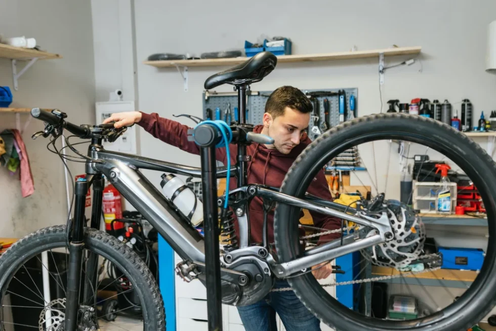 Technician performing a full tune-up on an eBike, including brake adjustments, battery testing, motor inspection, and lubrication for optimal performance